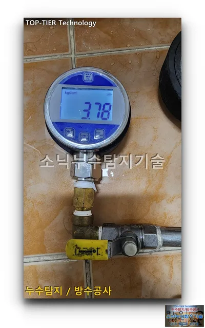 대구 달서구 대곡동 누수, 주황빛 타일 바닥에 놓인 디지털 압력계와 황동 연결 부속, 노란 밸브