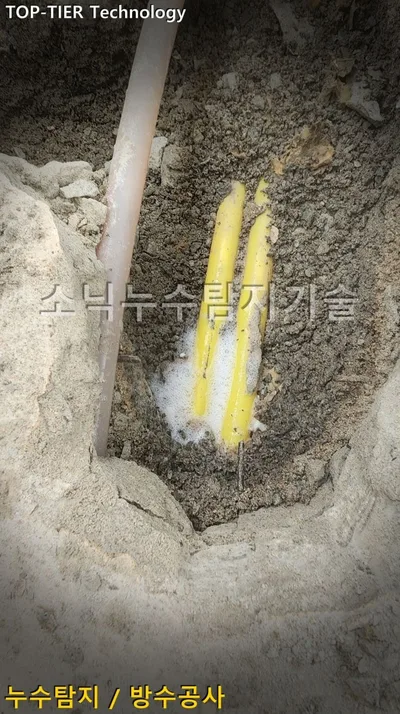 대구 달서구 호산동 누수, 깨 낸 바닥 속 노란 배관 두 가닥 위의 하얀 비눗물 거품과 옆을 지나는 분홍빛 배관