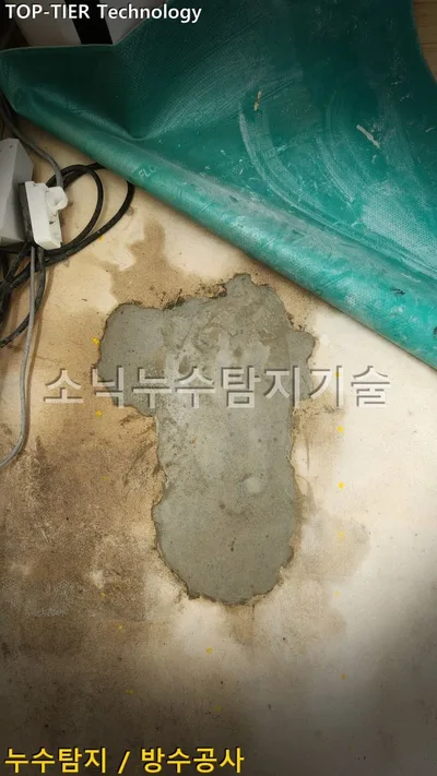 대구 달서구 호산동 누수, 초록 장판을 걷은 베이지색 바닥에 회색 시멘트로 메운 굴착 자리와 멀티탭