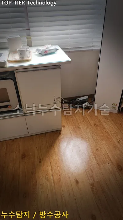 대구 달서구 호산동 누수, 나뭇결 장판을 다시 깐 바닥과 제자리에 놓인 흰 주방 수납장, 전자레인지와 블라인드 창