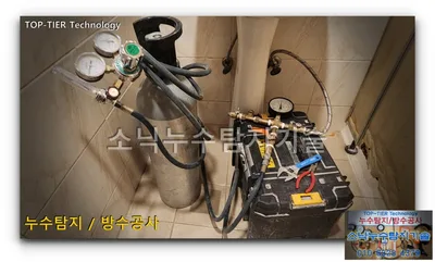 경산 사동 화장실에 세워 둔 은색 가스통과 공구가방 위 황동 부속·압력계