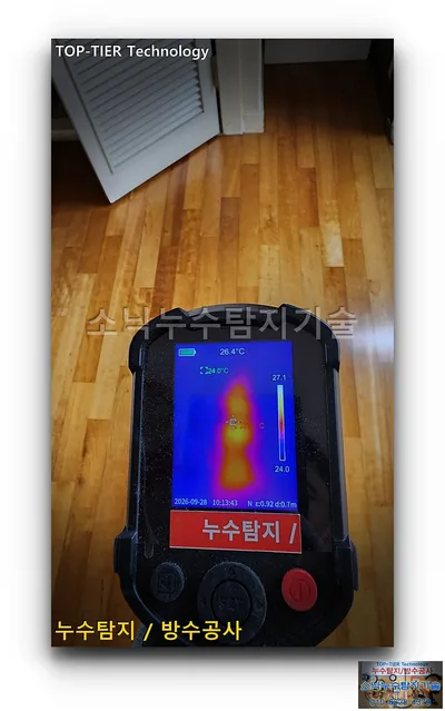 대구 수성구 신세계타운 누수, 나무 마루 위로 든 측정기 화면의 파란 바탕에 세로로 길게 나타난 주황·노란 색 분포