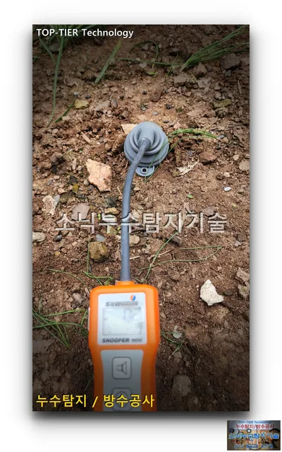 영양군 일월면 뒷마당 흙바닥에 흡입 캡을 대 둔 주황색 누수 가스 검출기